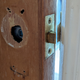 A close-up of a bathroom door, with its door handle missing.